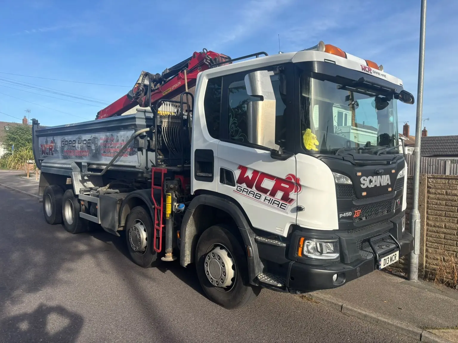 White WCR grab lorry with a folded red grab arm on a residential road