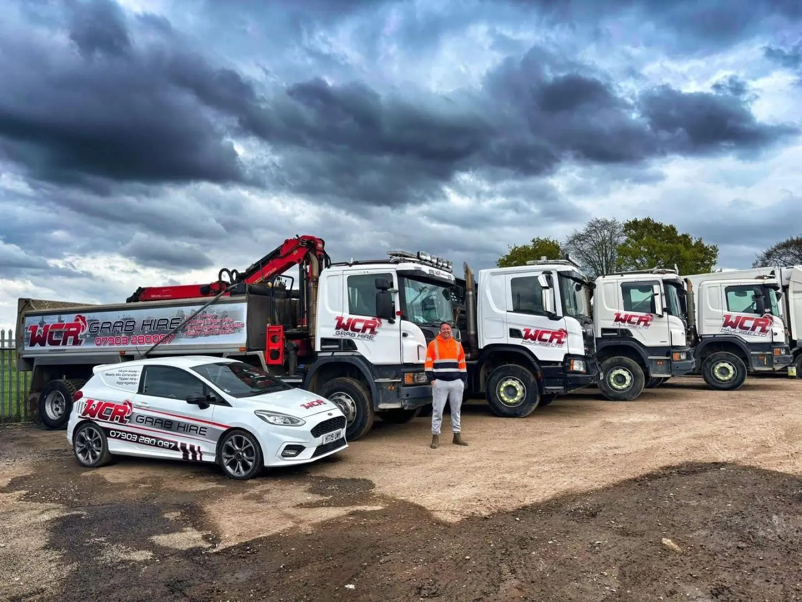 WCR lorries and a branded car lined up in a yard