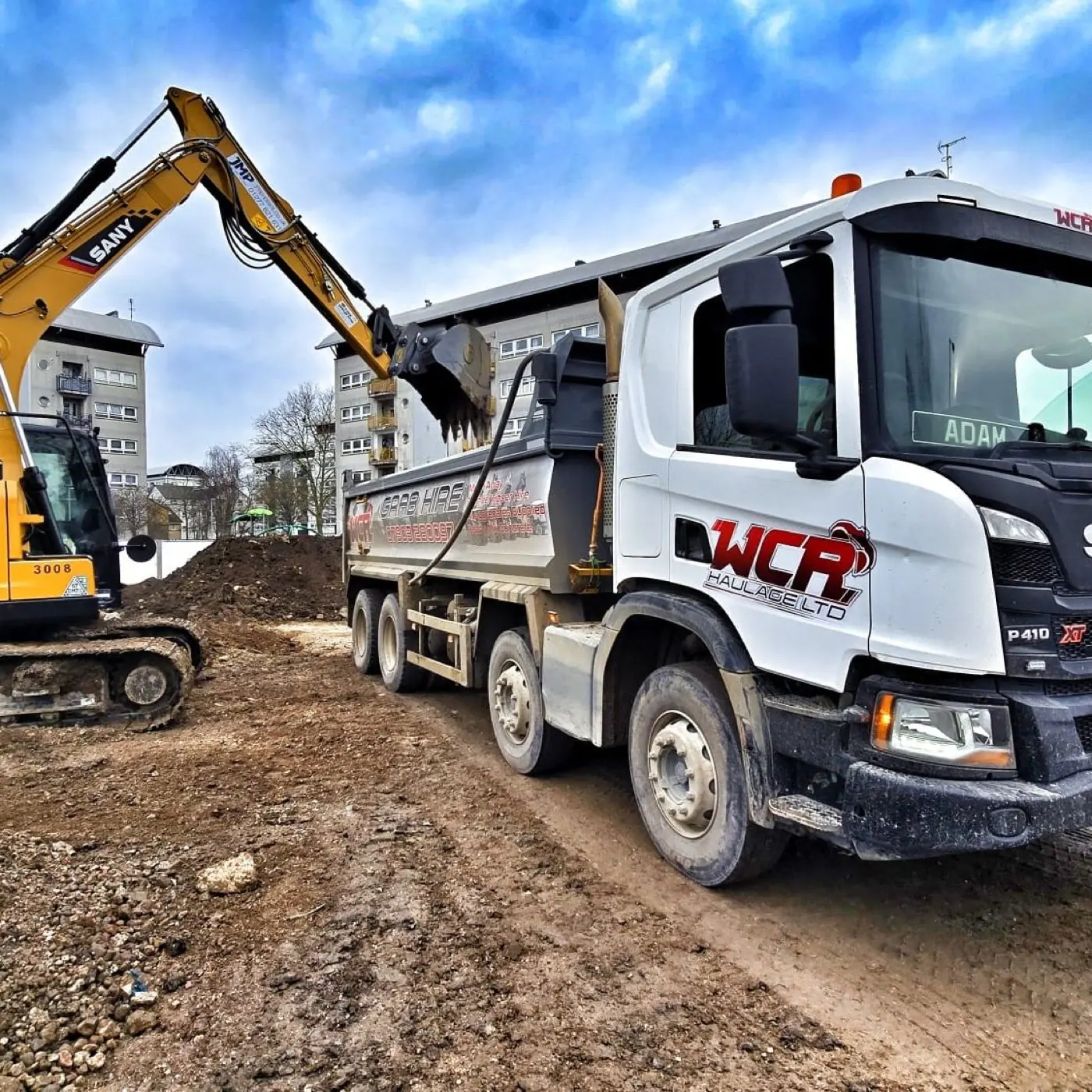 Yellow excavator beside a WCR tipper lorry on an earthwork site