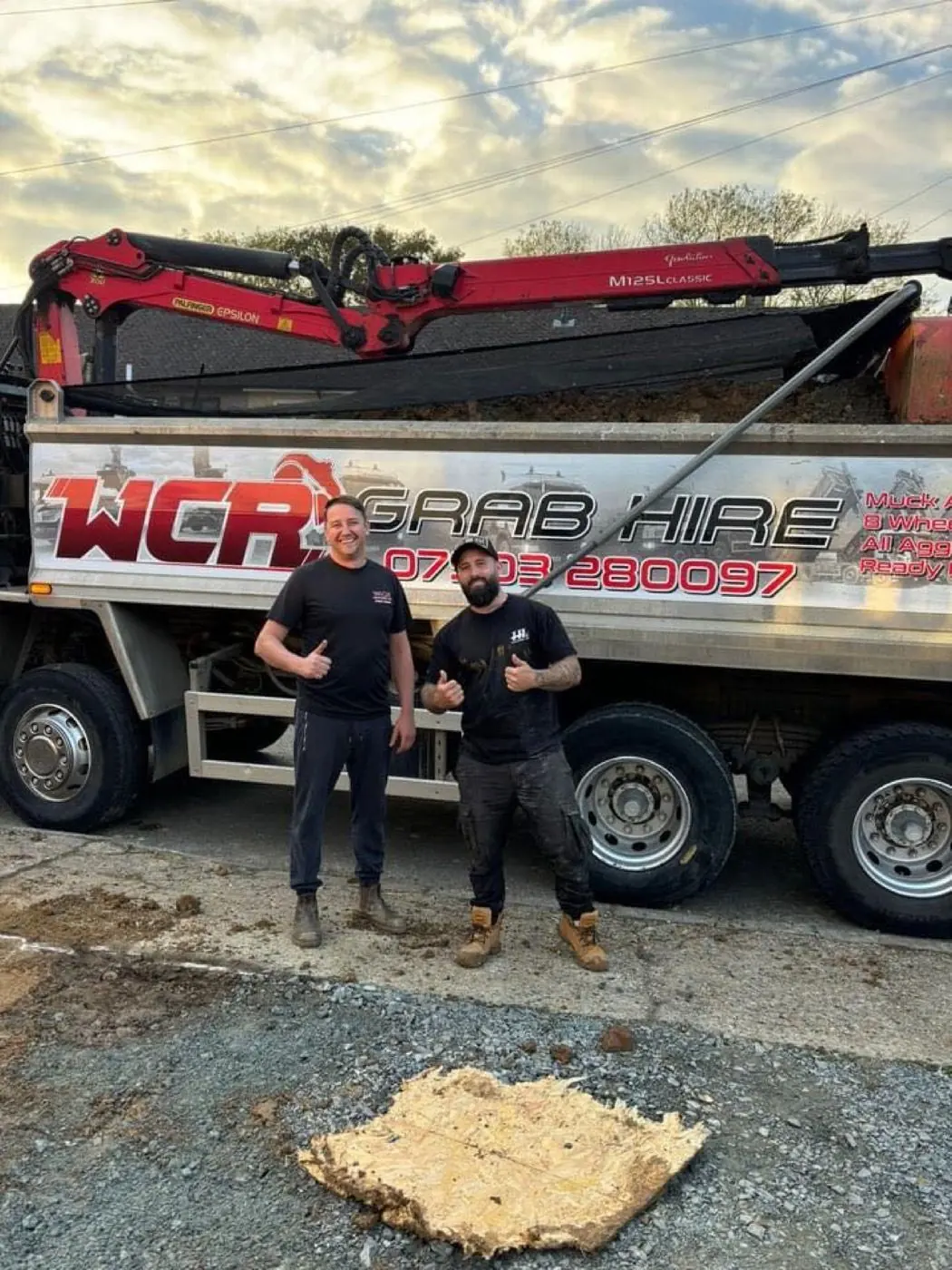 Two people standing beside a WCR grab lorry